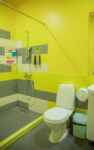 a yellow bathroom with a toilet and a shower at City Hostel Shymkent in Shymkent