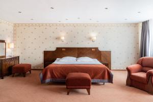 a bedroom with a large bed and two chairs at Hotel Alf in Krakow