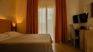 um quarto com uma cama, uma televisão e uma janela em Hotel San Teodoro em San Teodoro