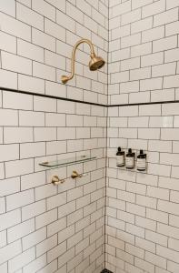 a white tiled shower with three pairs of shoes at The Imperial Hotel in Murwillumbah