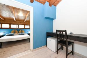 1 dormitorio con paredes azules, escritorio y silla en Hotel New Genziana, en Altavilla Vicentina