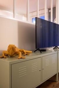 a toy dinosaur laying on top of a cabinet with a television at La Serrisienne 6 - Val d'Europe - Disneyland Paris - 9 Personnes in Chessy