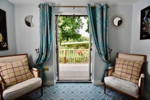 een woonkamer met 2 stoelen en een open deur bij Sheepwash Farm Rural Spa Retreat Cottages in Ticehurst