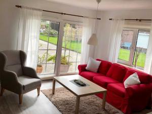 - un salon avec un canapé rouge et une chaise dans l'établissement Ferienhaus in Dornumersiel 20-032, à Dornumersiel