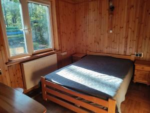 a bedroom with a bed in a wooden room at Dom w lesie nad rzeką z komnkiem in Mlądz