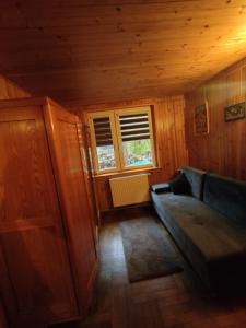 ein Wohnzimmer mit einem Sofa und einem Fenster in der Unterkunft Dom w lesie nad rzeką z komnkiem in Mlądz