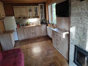 a kitchen with wooden cabinets and a fireplace at Dom w lesie nad rzeką z komnkiem in Mlądz