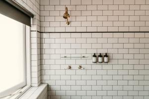 a white tiled shower with bottles on a shelf at The Imperial Hotel in Murwillumbah