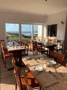 a dining room with tables and chairs with a view of the ocean at OA Surf Club in Bude