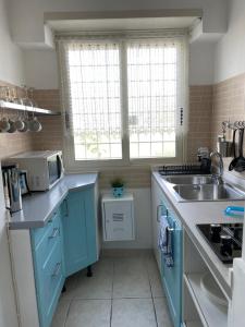 a blue kitchen with a sink and a microwave at Holiday Gels appartamento vacanza Ostia in Lido di Ostia