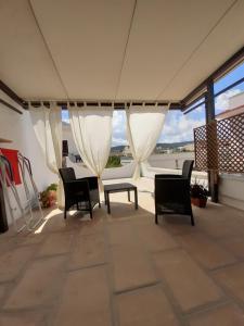 a patio with chairs and a table and windows at LA CASETTA in puglia in Montalbano