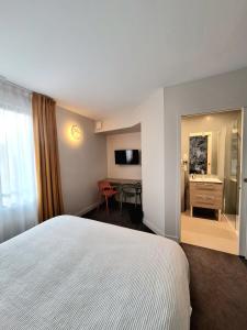 a hotel room with a white bed and a desk at Hôtel Les Herbes Folles in Mauregard