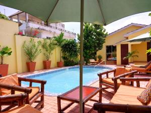 Bijilo的住宿－Bougainvillea House，一个带椅子和遮阳伞的游泳池