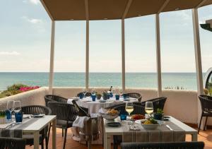 a restaurant with tables and chairs with the ocean in the background at Hotel Oasi Di Kufra in Sabaudia