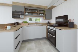 a kitchen with white cabinets and black appliances at The Malt Van - Beautiful, luxury static caravan in Aberlour