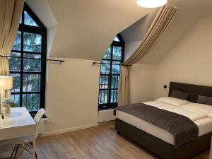 a bedroom with a bed and a desk and windows at Haus Karlich in Trausdorf an der Wulka