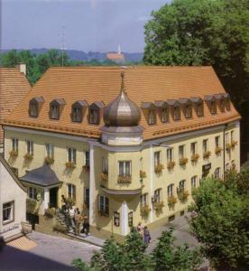 a large building with a tiled roof with people standing outside of it at Altstadthotel Schex in Altötting