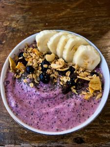 a bowl of a purple smoothie with bananas and nuts at Bronze Bungalows in Gili Meno