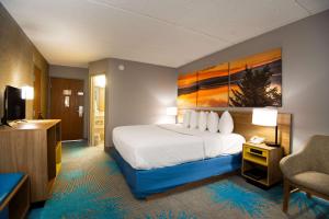 a hotel room with a bed and a chair at Days Inn by Wyndham Coeur d'Alene in Coeur d'Alene