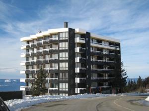 um grande edifício de apartamentos com neve à volta em Studio Chamrousse, 1 pièce, 4 personnes - FR-1-340-91 em Chamrousse