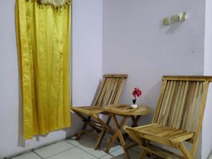 2 sillas y una mesa en una habitación con cortinas amarillas en Wisma Gahalta by Fans en Karawang