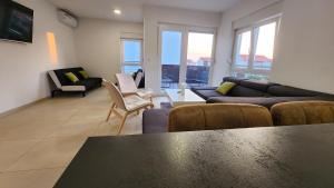 sala de estar con sofá, sillas y mesa en The Sands LUXE Pool Aparthotel 3, en Novalja