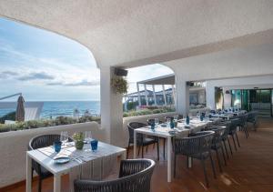 a restaurant with tables and chairs and the ocean at Hotel Oasi Di Kufra in Sabaudia