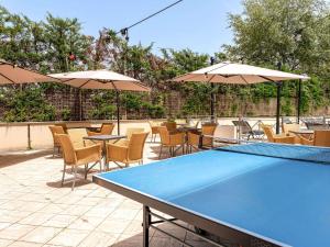 una mesa de ping pong azul con sillas y sombrillas en Novotel Roma Est, en Roma