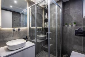 uma casa de banho com um lavatório e uma cabina de duche em vidro. em Boutique Studios near Airport em Pallíni
