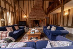 a living room with blue couches and a brick fireplace at Manor Farm Barn in Eye