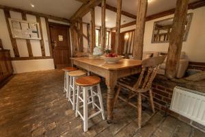 uma cozinha com uma mesa de madeira e bancos em Manor Farm Barn em Eye