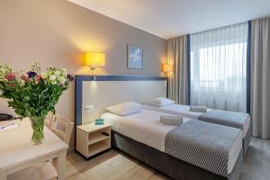 a hotel room with a bed and a table and flowers at Aurora Hotel Klaipeda in Klaipėda