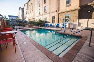 einen Pool mit Stühlen, einem Tisch und einem Gebäude in der Unterkunft Hampton Inn Grand Junction in Grand Junction