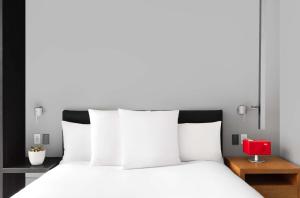 a white bed with white pillows and a red lamp at Andaz 5th Avenue-a concept by Hyatt in New York