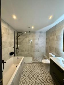 a bathroom with a tub and a toilet and a sink at Villa Preciosa in Les tres Cales