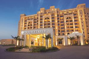 un grand bâtiment avec un panneau devant lui dans l'établissement DoubleTree by Hilton Resort & Spa Marjan Island, à Ras al Khaimah