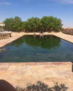 una persona è seduta in una piscina d'acqua di Beit Dina a Siwa