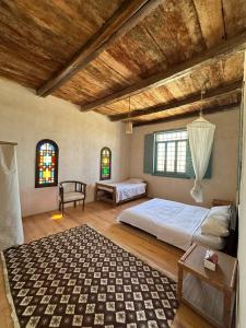 a bedroom with a bed and a table and two windows at Beit Dina in Siwa