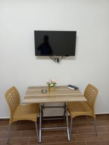 a table with two chairs and a television on a wall at EMILE ALTWAL in Madaba
