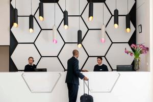 a man in a suit standing in front of a reception desk with three people at Barceló Fès Medina in Fez