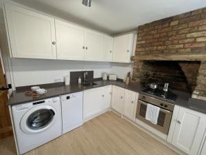 uma cozinha com uma máquina de lavar roupa e uma parede de tijolos em Poplar Cottage Farnborough Kent em Orpington