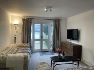 ein Wohnzimmer mit einem Sofa und einem TV in der Unterkunft Poplar Cottage Farnborough Kent in Orpington