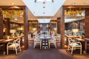 a restaurant with wooden tables and white chairs at Tallink Hotel Riga in Rīga