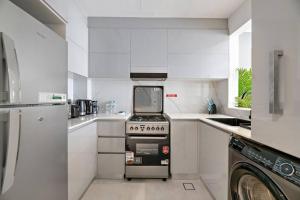 a white kitchen with a stove and a microwave at StoneTree - Modern 1BR in Binghatti Creek in Dubai