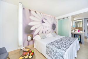 ein Schlafzimmer mit einem Bett mit einer Blume an der Wand in der Unterkunft Barceló Illetas Albatros - Adults Only in Illetas