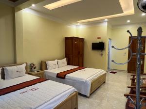 a hotel room with two beds and a tv at Thien Son Guesthouse in Ha Giang
