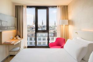 um quarto de hotel com uma cama, uma secretária e uma janela em Barceló Hamburg em Hamburgo