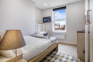 ein Schlafzimmer mit einem Bett mit einer Lampe und einem Fenster in der Unterkunft Modern Apartments in the Heart of Middlesbrough 2 in Middlesbrough