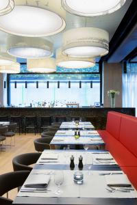 a row of tables in a restaurant with red chairs at Barceló Hamburg in Hamburg