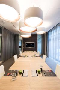 uma sala de conferências com uma mesa longa e cadeiras brancas em Barceló Hamburg em Hamburgo